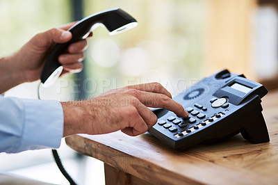 Buy stock photo Cropped shot of a man dialing a number on a telephone at work