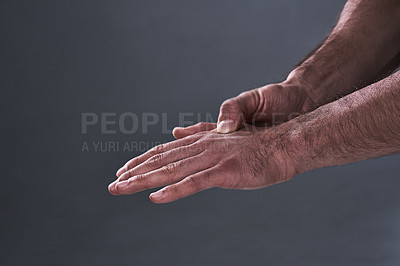 Buy stock photo Shot of an unrecognizable man rubbing his injured hand during a workout