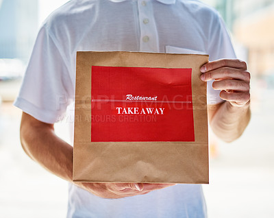 Buy stock photo Cropped shot of a delivery man holding a restaurant takeaway