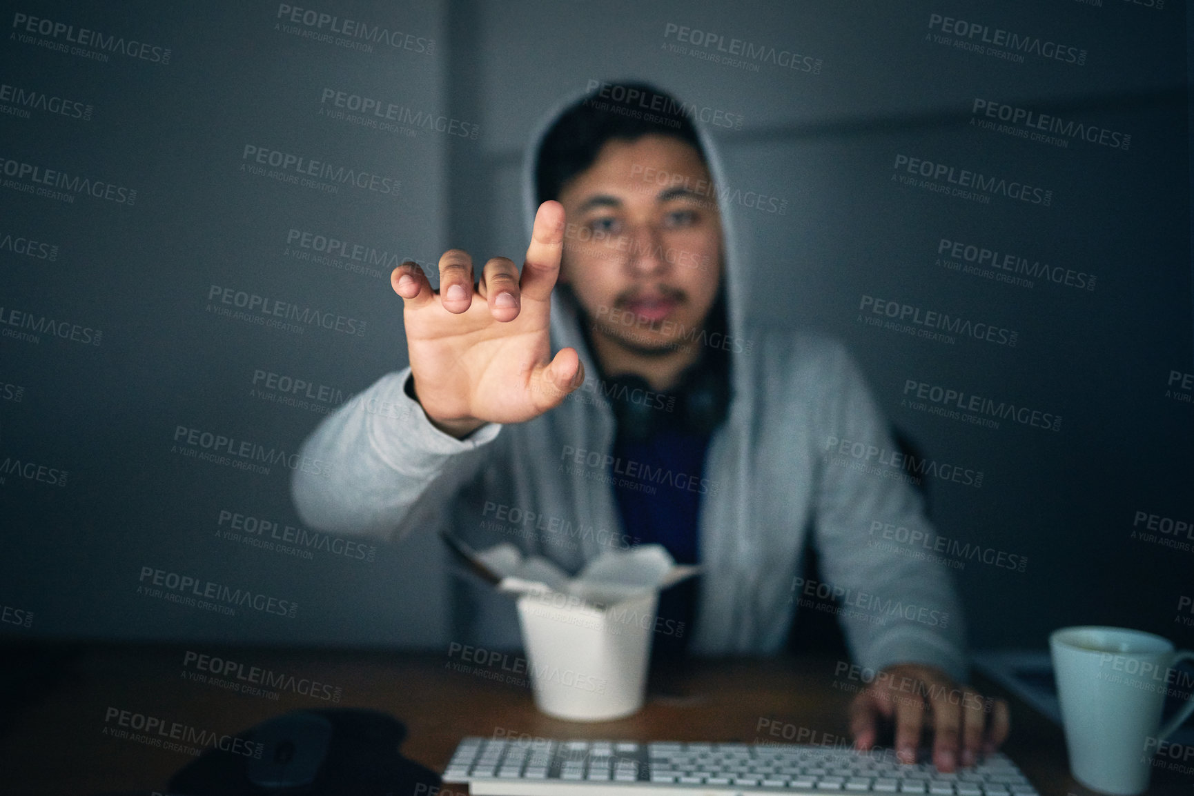 Buy stock photo Shot of a young man using an unseen digital interface while sitting at a computer late at night