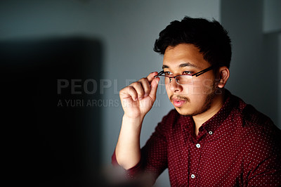 Buy stock photo Shot of a young male designer working on his computer late at night