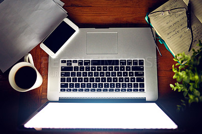 Buy stock photo High angle shot of a laptop and other items sitting on a desk in the evening