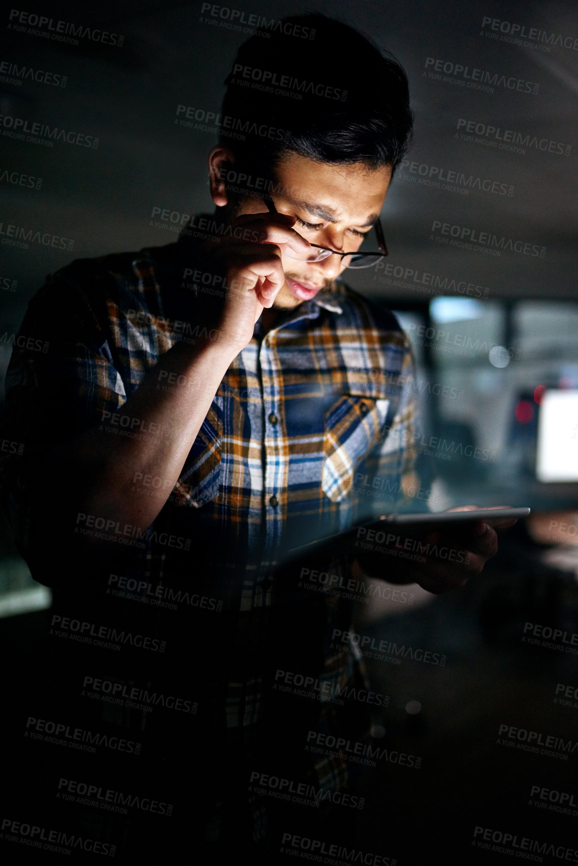 Buy stock photo Shot of a male designer working on a digital tablet late in the office