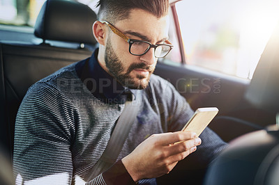 Buy stock photo Shot of a young designer using a cellphone in a car