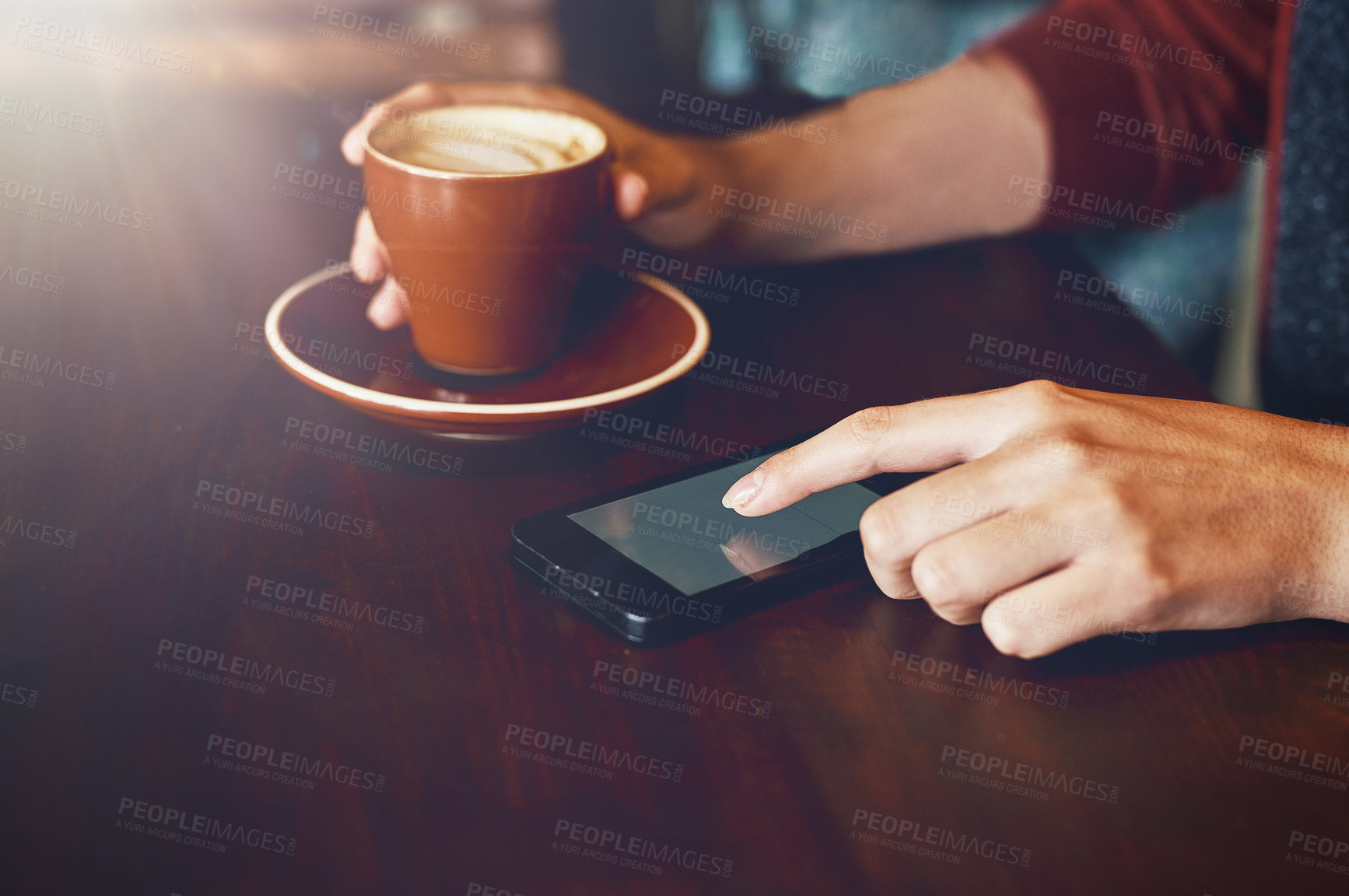 Buy stock photo Closeup shot of an unidentifiable woman enjoying a cup of coffee while using her phone in a cafe