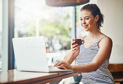 Buy stock photo Shot of a young woman using her laptop in a coffee shop