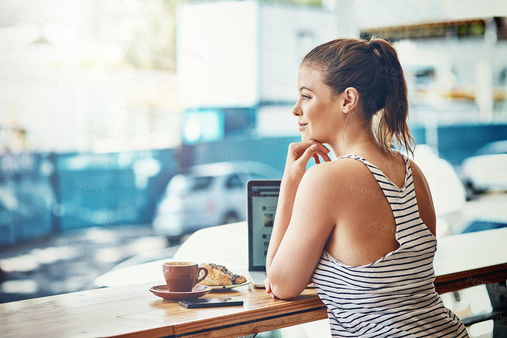 Buy stock photo Shot of a thoughtful young woman using her laptop in a coffee shop