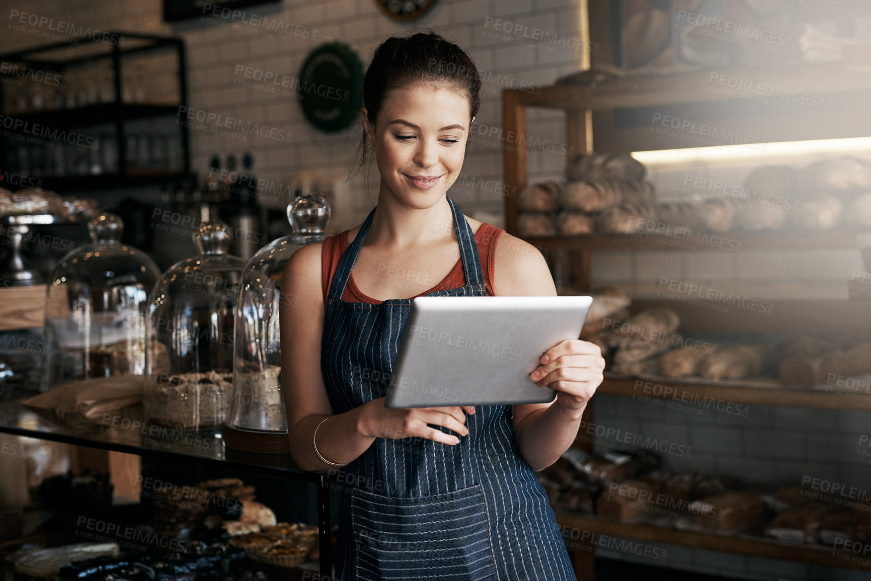 Buy stock photo Shot of a young woman using a digital tablet while working in a coffee shop