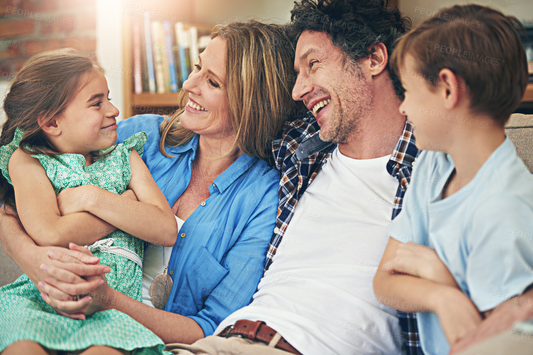 Buy stock photo Relax, parents and happy children on sofa for love, playing and bonding together in living room. Lens flare, mother and father with kids on couch for embrace, family reunion or weekend break in home