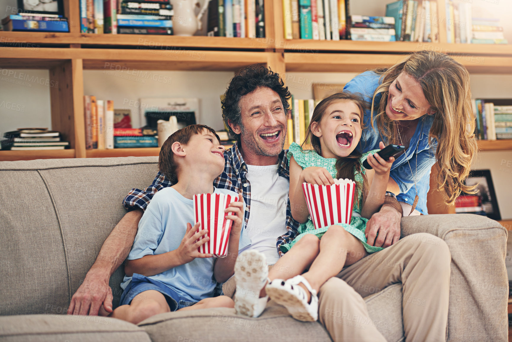 Buy stock photo Happy family, relax and laughing with popcorn for funny movie, weekend or holiday on living room sofa at home. Mom, dad and young children with smile for comedy, series or streaming service at house