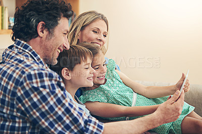Buy stock photo Shot of a happy family using a digital tablet together at home