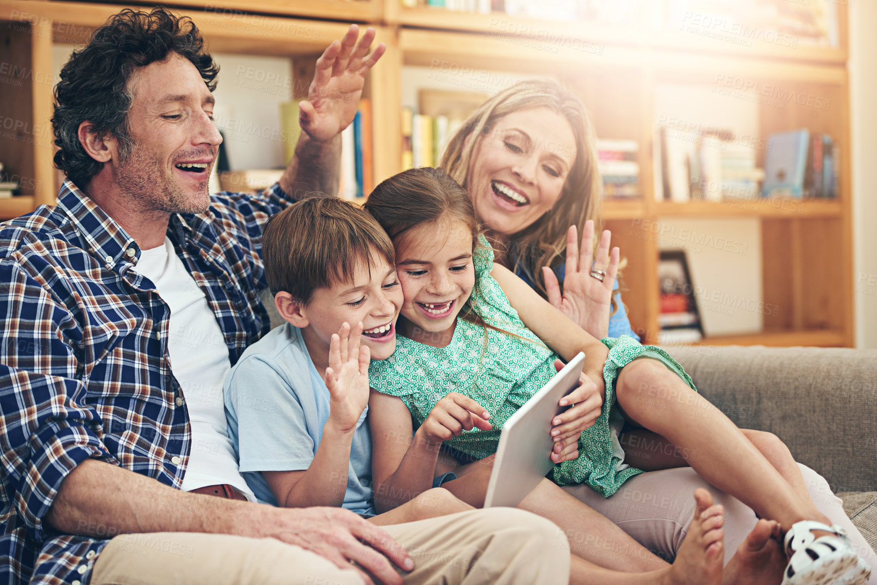 Buy stock photo Shot of a happy family making a video call on their digital tablet together at home