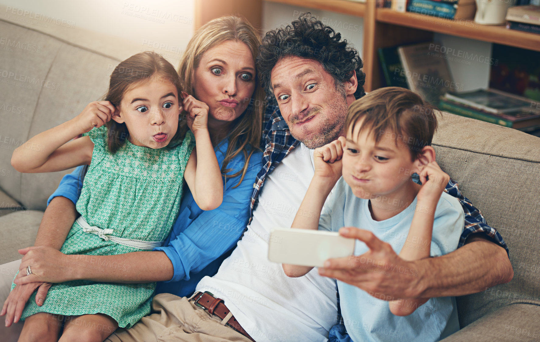Buy stock photo Shot of a family taking a selfie together on a mobile phone at home
