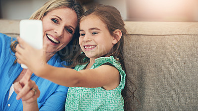 Buy stock photo Happy mother, child and relax with selfie on sofa for picture, memory or bonding together at home. Mom, daughter or kid with smile for photography, capture or moment on living room couch at house