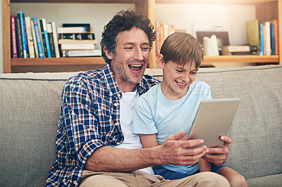 Buy stock photo Shot of a happy father and his son using a digital tablet together at home