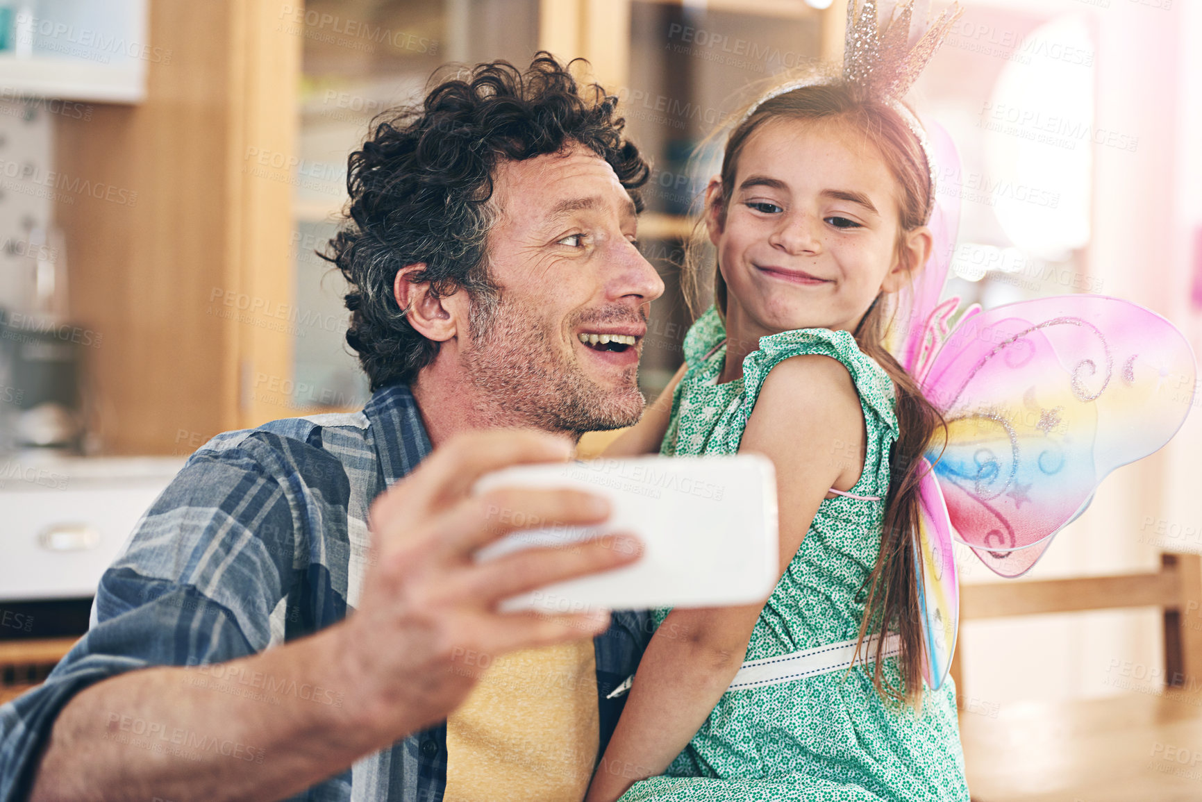 Buy stock photo Shot of a happy father and daughter taking a selfie together on a mobile phone at home