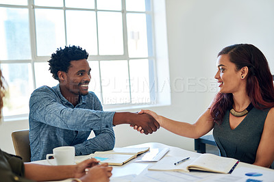 Buy stock photo Shot of happy colleagues shaking hands during a meeting in a modern office