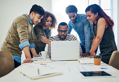 Buy stock photo Shot of a group of colleagues using a laptop together in a modern office