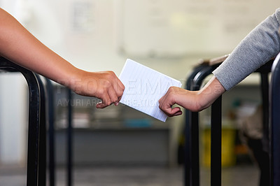 Buy stock photo Shot of two unidentifiable schoolchildren passing a note in class