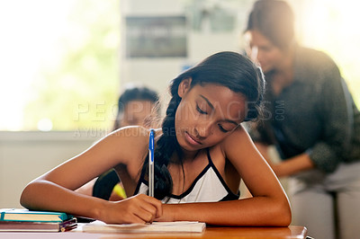 Buy stock photo Shot of a young schoolgirl doing her homework in class