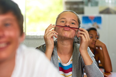Buy stock photo Shot of a young schoolgirl pulling a funny face while sitting in class