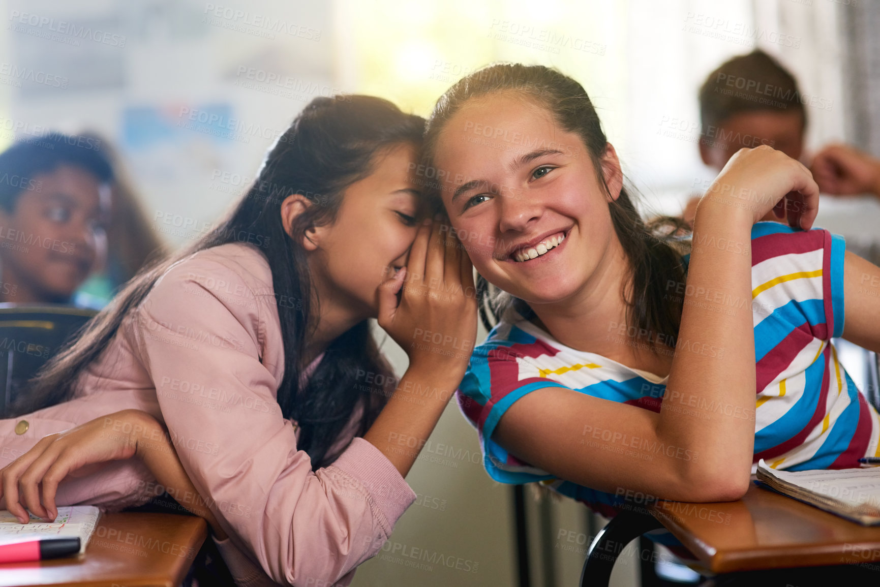 Buy stock photo Shot of a young schoolgirl whispering a secret to her friend in class