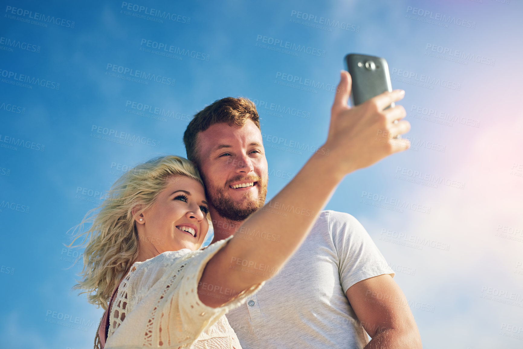 Buy stock photo Relax, smile and couple with selfie by blue sky for adventure, online post and memory of vacation. Low angle, man and woman with digital picture for social media, holiday update and travel in nature