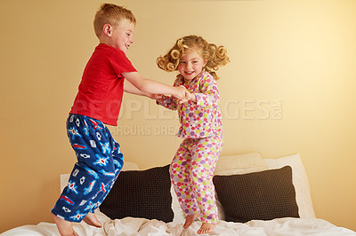 Buy stock photo Shot of two little siblings jumping on the bed together at home