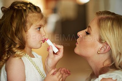 Buy stock photo Cropped shot of a mother applying lipstick to her little daughter at home