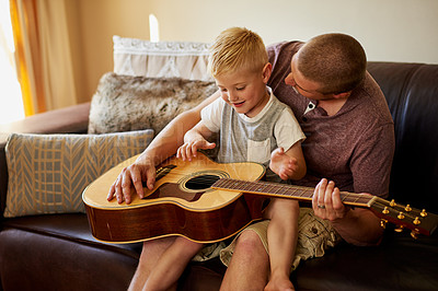 Buy stock photo Cropped shot of a father and his little son playing the guitar together at home