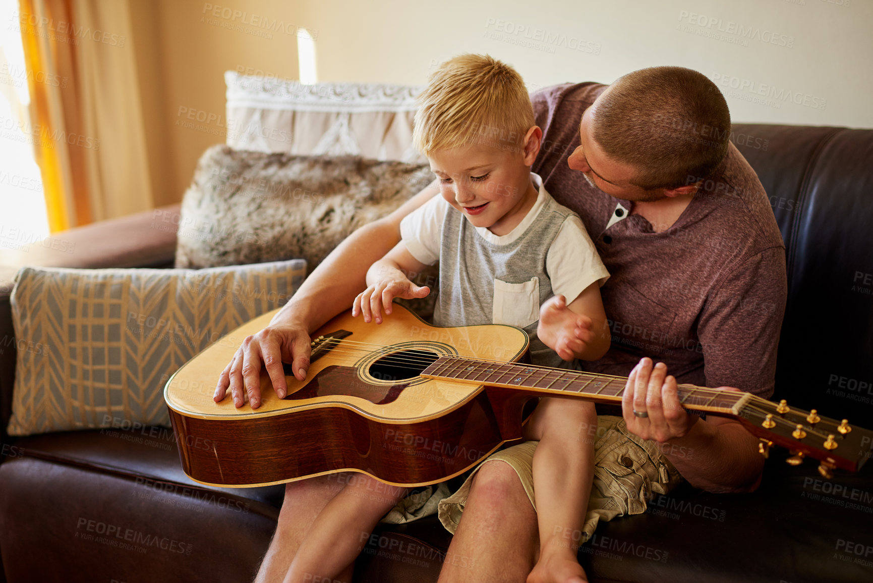 Buy stock photo Cropped shot of a father and his little son playing the guitar together at home
