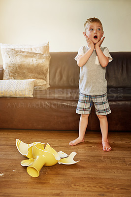 Buy stock photo Shot of a little boy looking shocked after breaking a vase at home