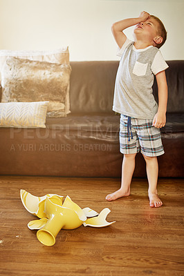 Buy stock photo Shot of a little boy looking worried after breaking a vase at home