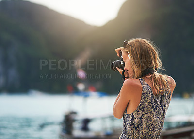 Buy stock photo Cropped shot of a young woman taking photos with her camera at the beach