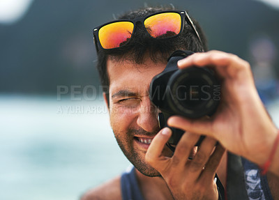Buy stock photo Portrait of a young man taking photos with his camera at the beach