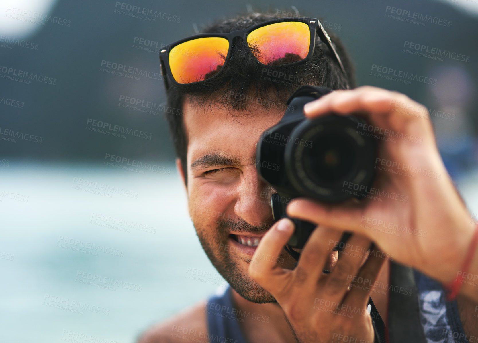 Buy stock photo Portrait of a young man taking photos with his camera at the beach