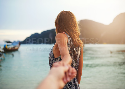 Buy stock photo Shot of a young woman leading someone by the hand at the beach
