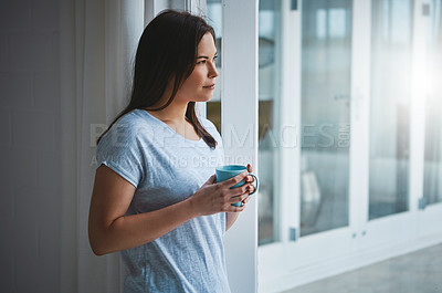 Buy stock photo Cropped shot of an attractive young woman enjoying a coffee by her patio door