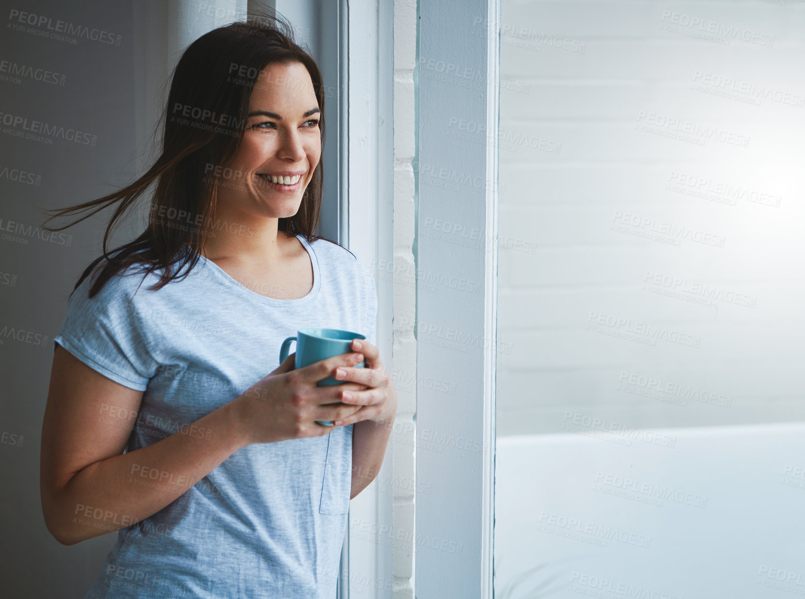 Buy stock photo Cropped shot of an attractive young woman enjoying a coffee by her patio door