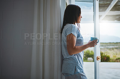 Buy stock photo Rearview shot of an attractive young woman enjoying a coffee by her patio door