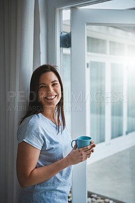 Buy stock photo Cropped shot of an attractive young woman enjoying a coffee by her patio door