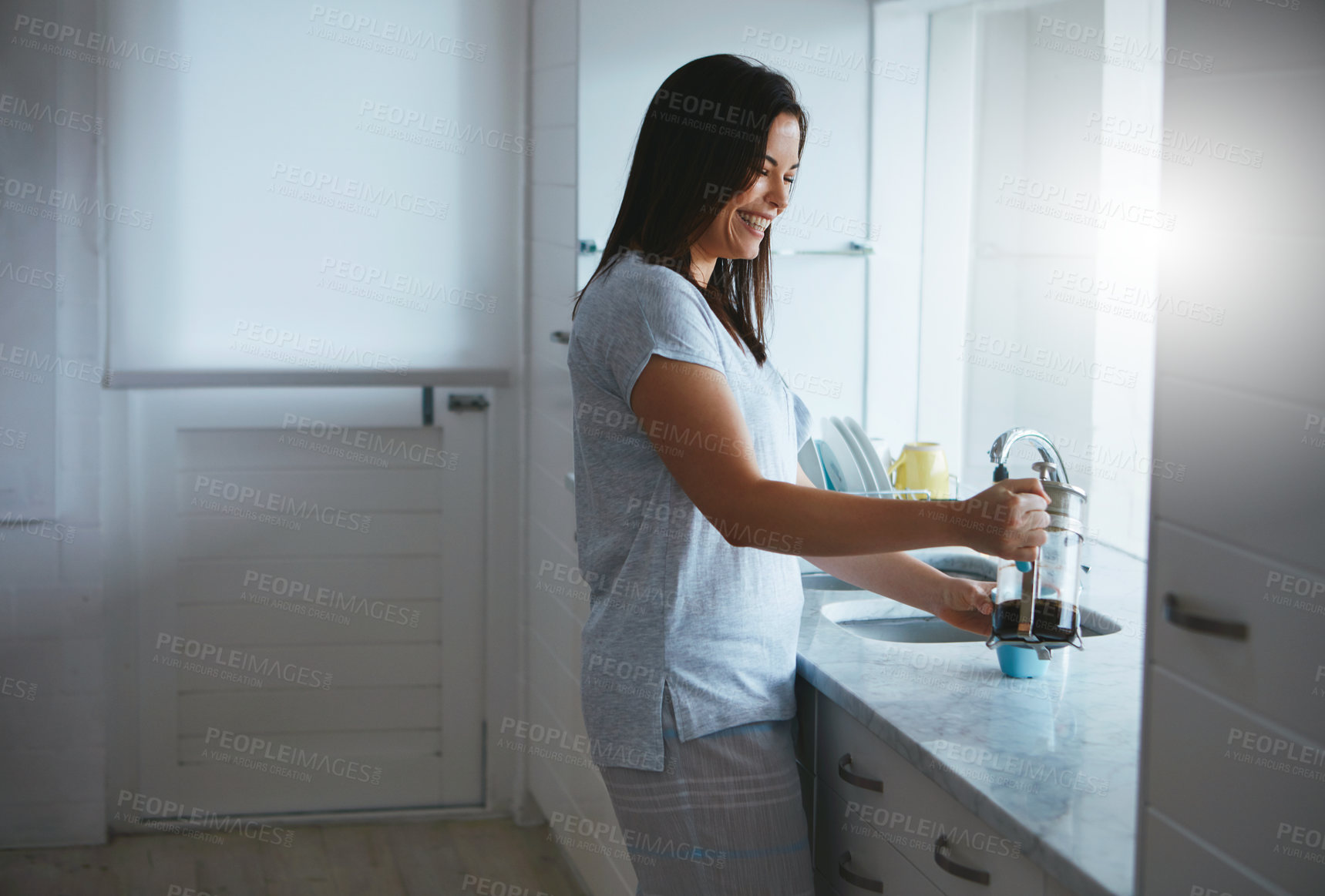 Buy stock photo Cropped shot of an attractive young woman preparing a pot of coffee in the kitchen