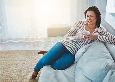 Buy stock photo Shot of a young woman relaxing on the sofa and enjoying a warm drink at home