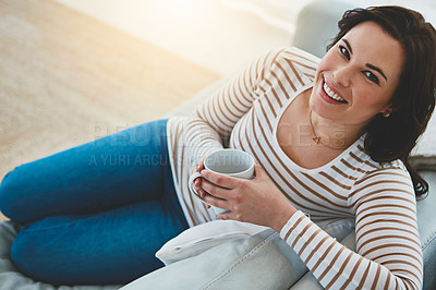 Buy stock photo Shot of a young woman relaxing on the sofa and enjoying a warm drink at home