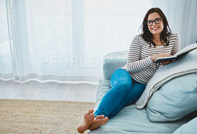 Buy stock photo Shot of a young woman relaxing on the sofa and reading a book at home