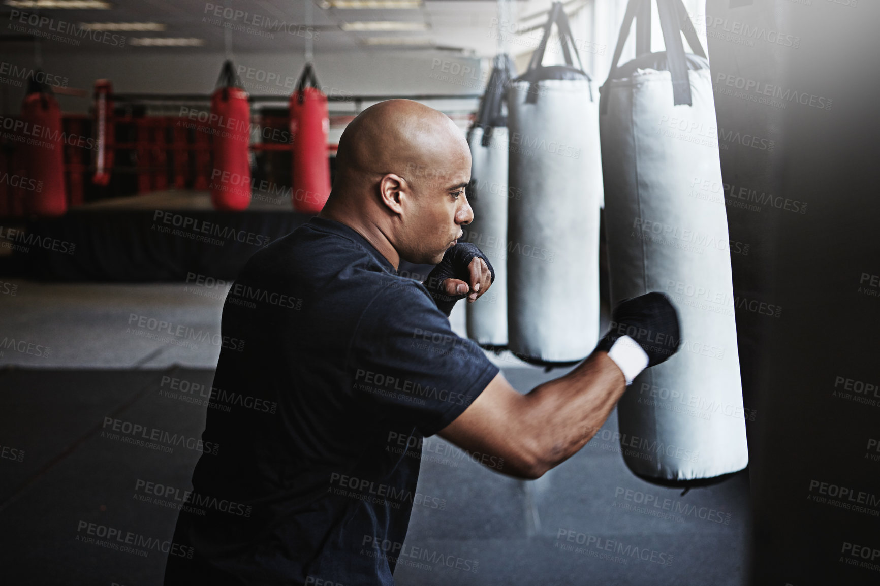 Buy stock photo Exercise, punching bag and man in MMA gym for boxing, challenge or competition training. Power, muscle and serious champion boxer at workout with confidence, fight and energy in sports fitness club.