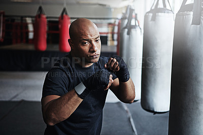 Buy stock photo Fitness, punching and man in MMA gym for exercise, boxing challenge or competition training. Power, muscle and champion boxer at workout with confidence, fight and energy in sports club with gloves.