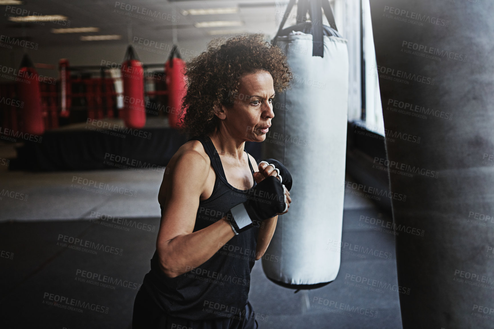 Buy stock photo Gym, punching bag and mature woman in boxing for workout, challenge or competition training. Power, muscle and strong champion boxer in exercise with confidence, fight and energy in MMA sports club.