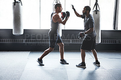 Buy stock photo Shot of a male boxer practising his moves with his coach