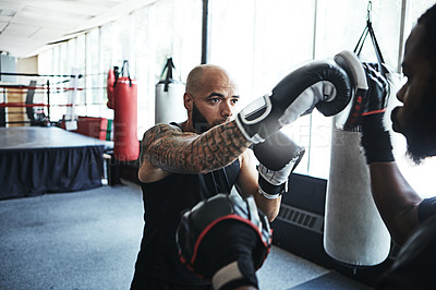 Buy stock photo Shot of a male boxer practising his moves with his coach